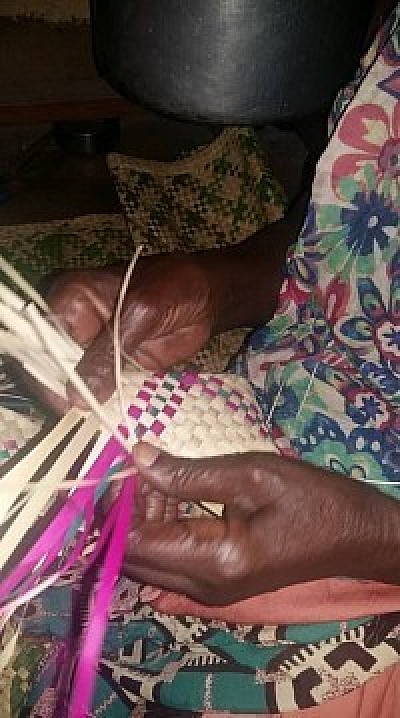 A refugee woman weaves basket and mats from reeds and palm leaves to generate extra income for livelihood